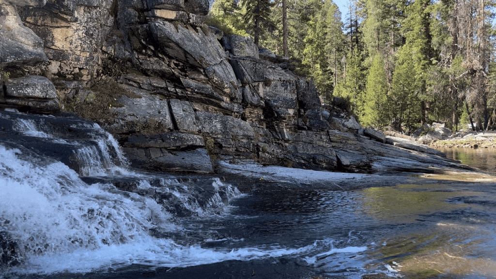 A small waterfall cascading over a rocky cliff, with clear, flowing water and a textured rock face.