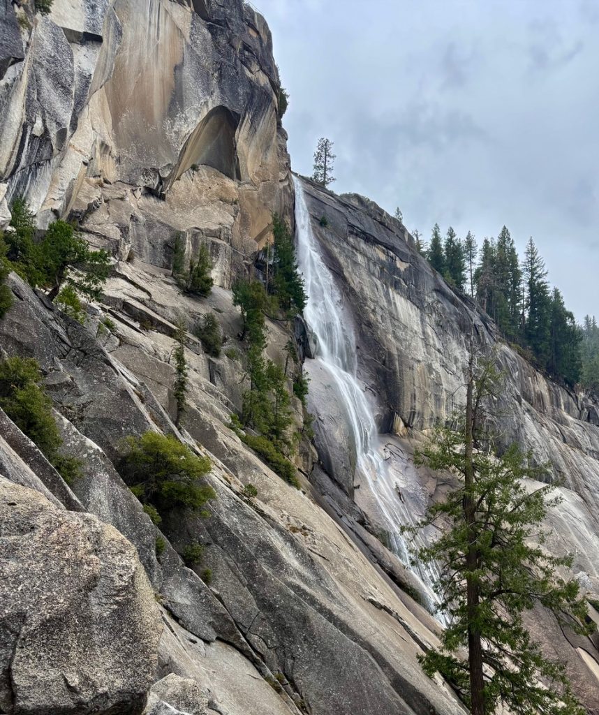 Mountainous landscape with a trail, a sign saying "Clark Point," and a distant waterfall.