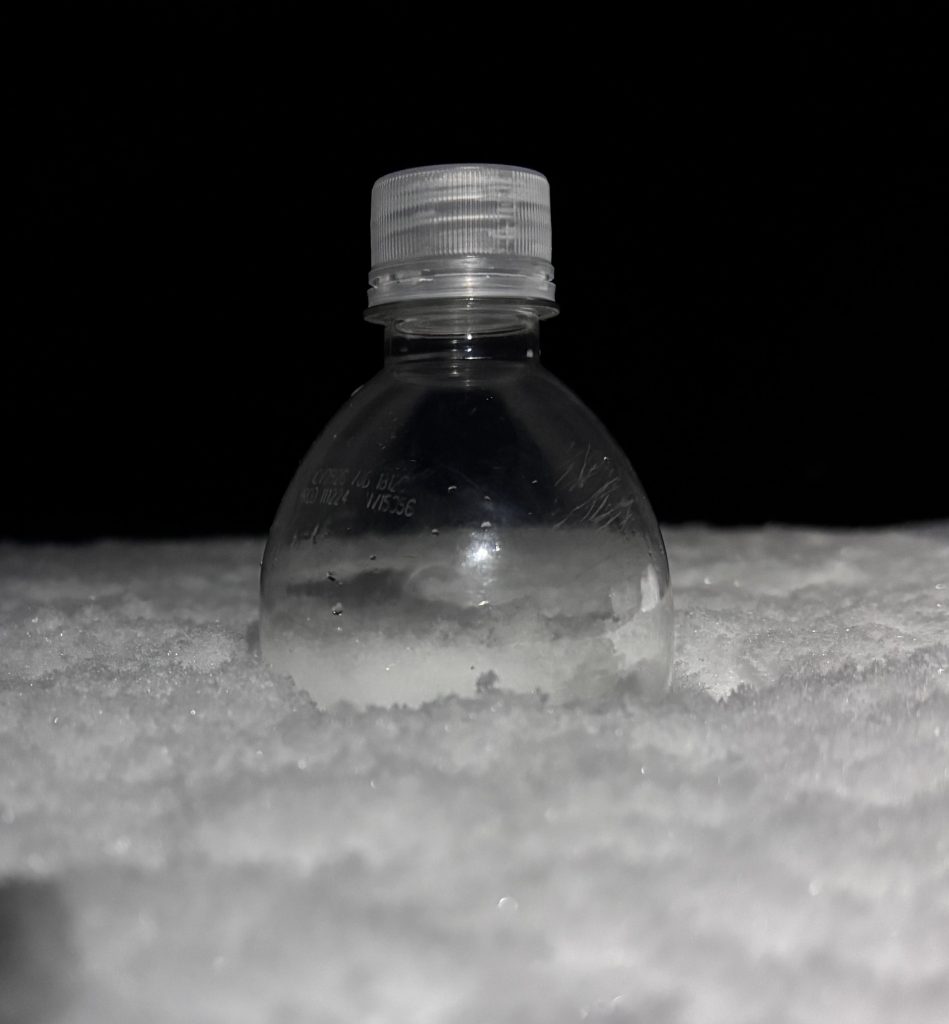 The top of a smart water bottle peeks out above fresh snowfall