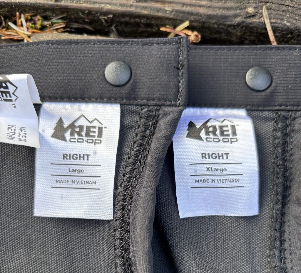 Close-up comparison of REI Co-op gaiters in Large and X-Large sizes, showing “Right” leg tags and “Made in Vietnam” labels on black fabric.