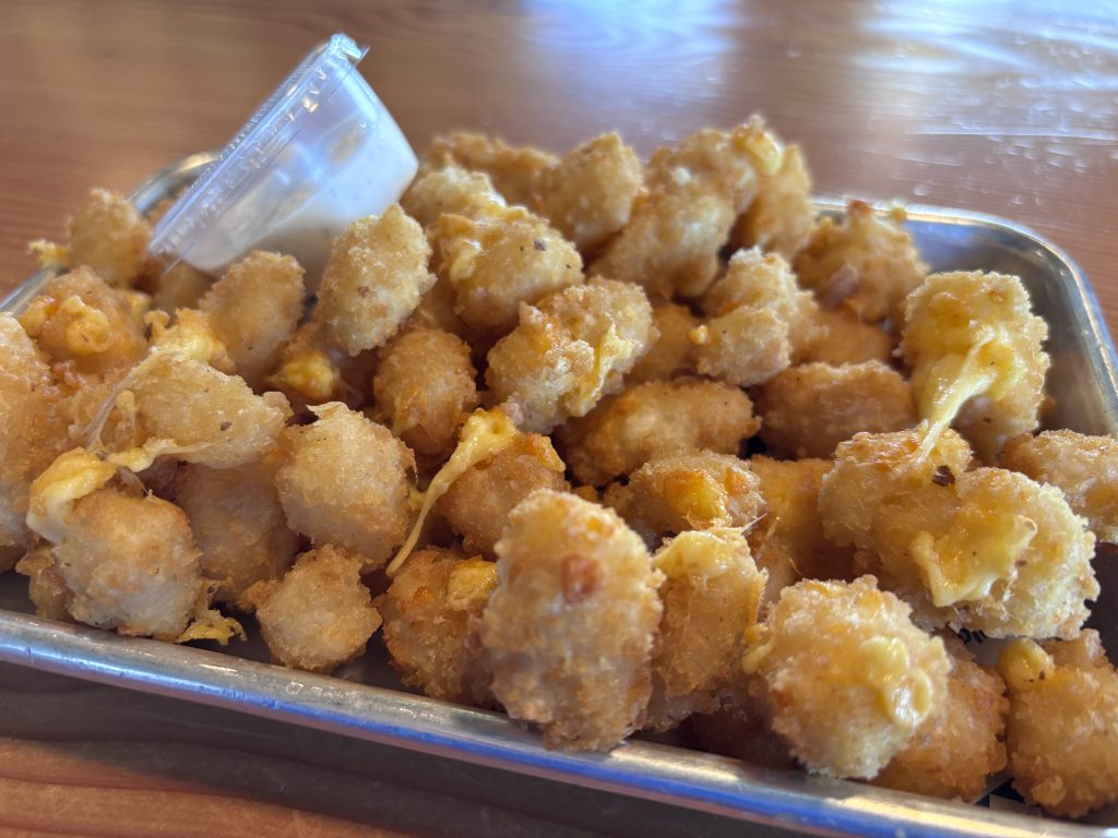 Close-up of fried cheese curds served on a metal tray with a cup of ranch dressing at the Tillamook Creamery cafe.